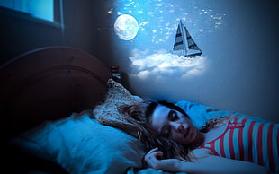 girl wearing white and red striped tank top lying on bed during nighttime